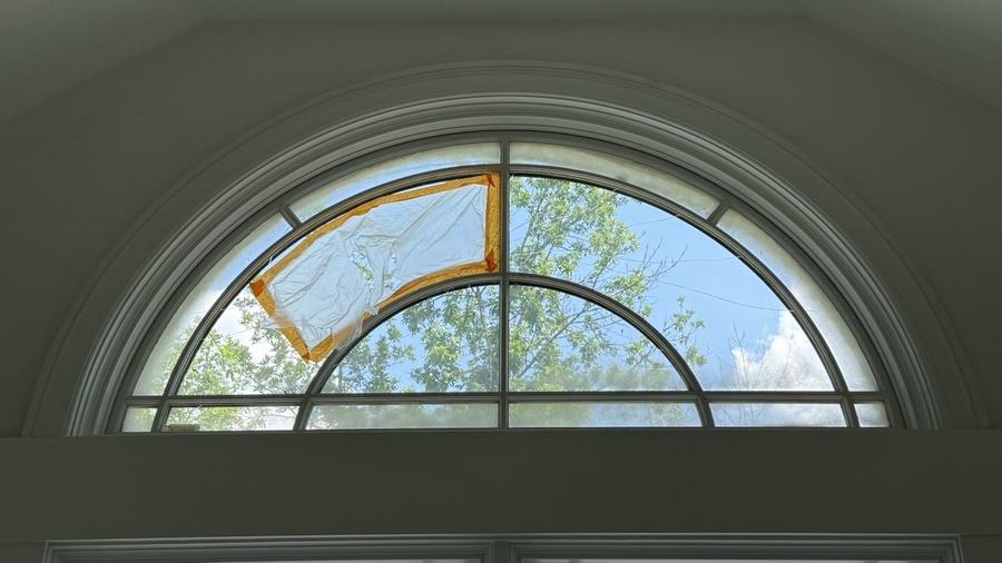 Arched fanlight window with one damaged glass segment marked for custom replacement