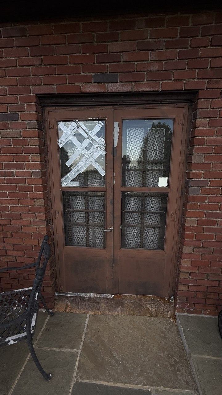 Broken glass pane in a wood entry door, temporarily taped before replacement