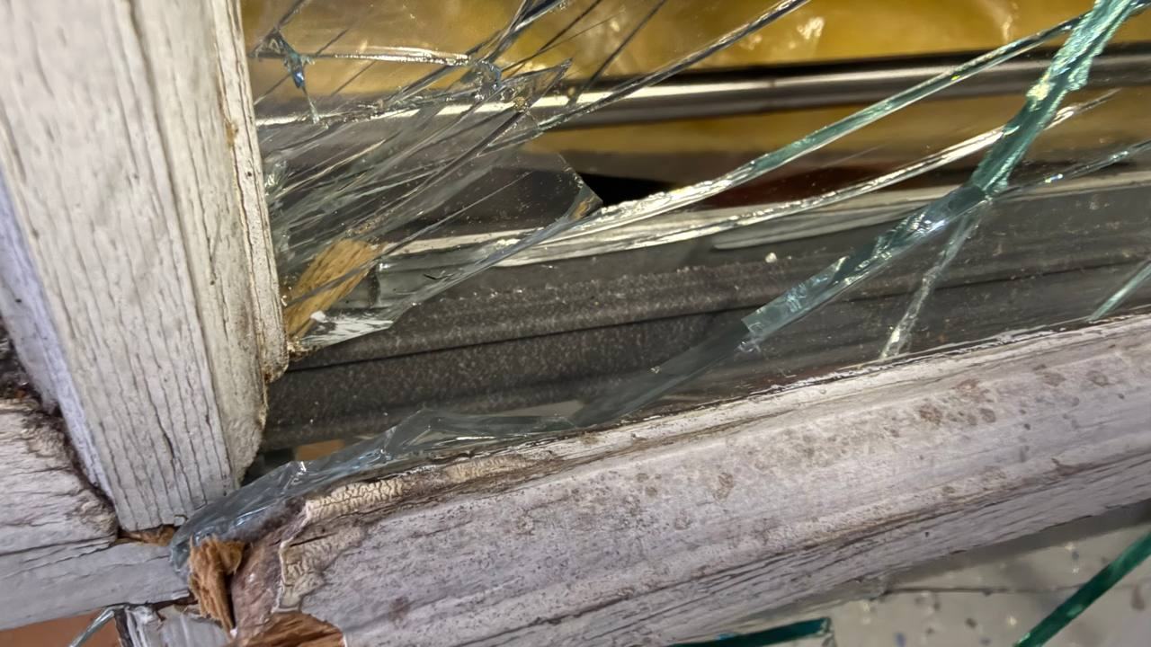 Broken window glass shattered inside a wood sash, temporarily covered before replacement — WindowServ, New Jersey