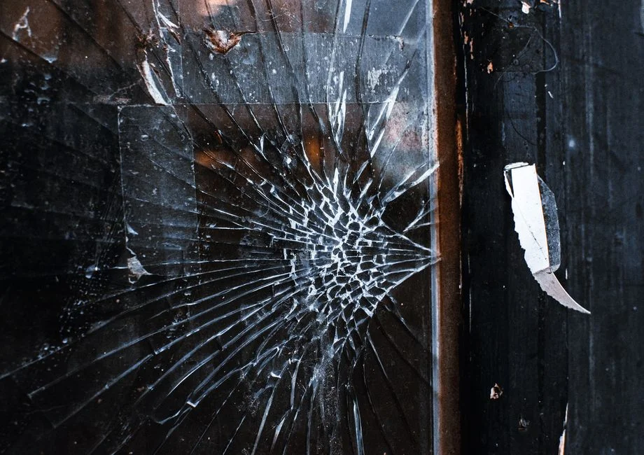 Close-up of a cracked commercial storefront glass pane in a busy urban setting - commercial window repair newark
