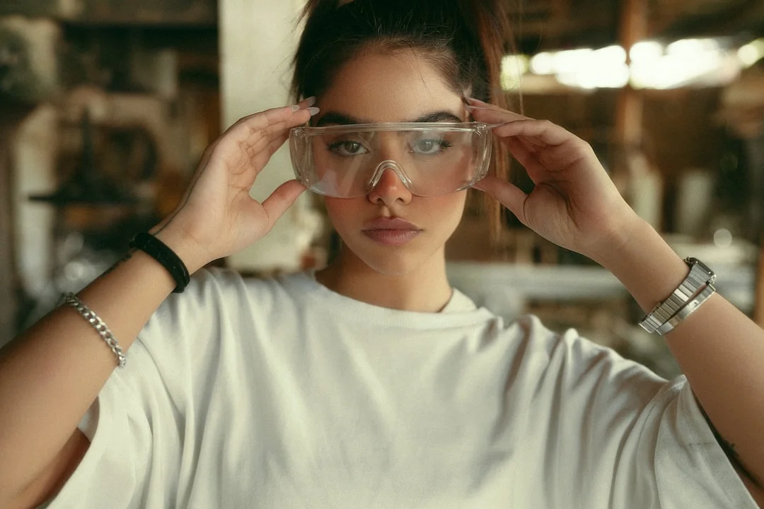 Technician wearing safety glasses tilting a wood window sash inward for removal